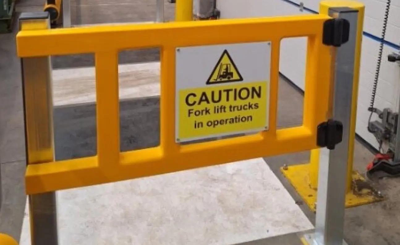 Warehouse pedestrian safety barrier system with yellow guard rails separating walkways from racking